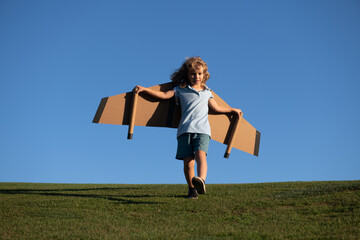 Cute dreamer boy playing with a cardboard airplane on sky. Childhood. Fantasy, imagination.