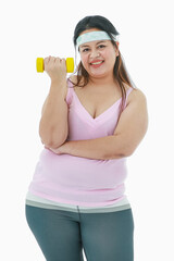 Portrait isolated studio shot of Asian happy healthy strong big fat oversize girl in sport clothing leggings pants with headband stand crossed arm smiling holding dumbbell in front white background