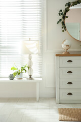 White chest of drawers and mirror near window indoors. Interior design