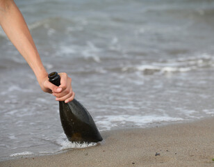 hand grabbing the beached glass bottle that can hold a secret message or the treasure map