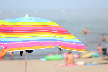 parasol umbrella on the beach with swimmers having fun during the summer holidays