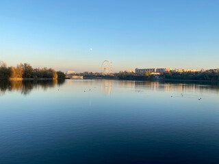 Fototapeta premium Lake with city reflection on sunset landscape view of