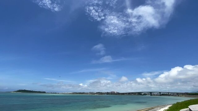 OKINAWA, JAPAN - JUNE 2021 : View of Senaga island and beach (Ocean or sea). Clear blue summer sky, clouds and air plane. Wide view real time shot in daytime. Holiday, vacation and resort concept.