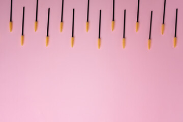 Disposable brushes for eyelashes and eyebrows on pink background.