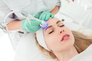 Naklejka premium young woman in cosmetology clinic. Rf skin tightening, facelift . Hardware cosmetology