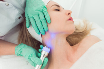 Naklejka premium young woman in cosmetology clinic. Rf skin tightening, facelift . Hardware cosmetology