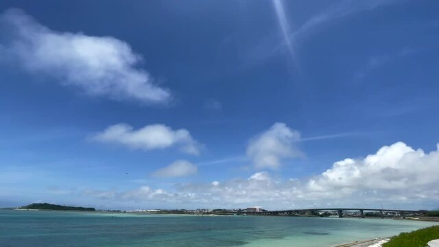 OKINAWA, JAPAN - JUNE 2021 : View of Senaga island and beach (Ocean or sea). Clear blue summer sky, clouds and air plane. Wide view real time shot in daytime. Holiday, vacation and resort concept.