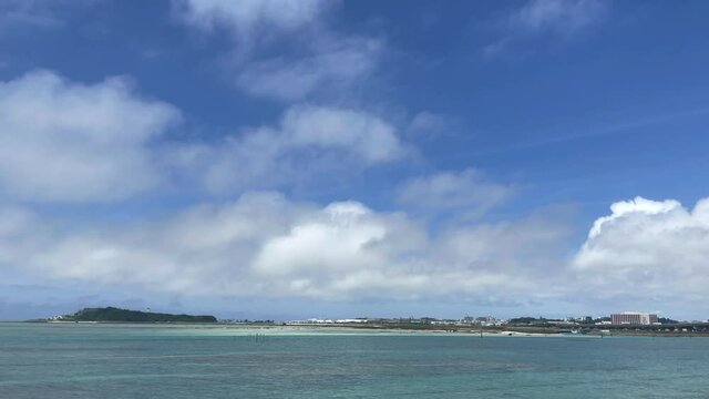 OKINAWA, JAPAN - JUNE 2021 : View of Senaga island and beach (Ocean or sea). Clear blue summer sky, clouds and air plane. Wide view real time shot in daytime. Holiday, vacation and resort concept.