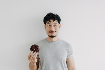 Happy Asian man holding a chocolate cookie isolated on white background.