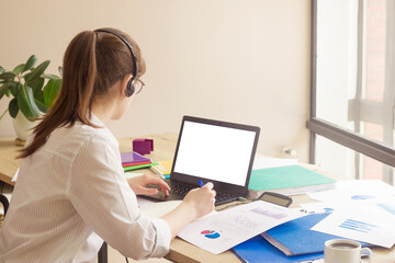 Empty space for text. A laptop with a blank white screen. A young  manager girl at her workplace in the office.