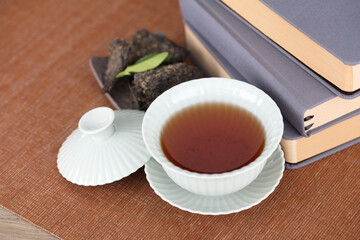 Gaiwan tea and tea leaves beside a few books