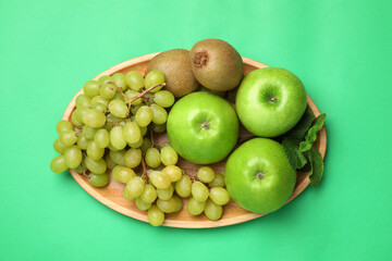 Fresh ripe apples, kiwis, grape and mint on green background, top view