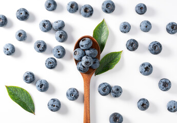 Blueberries and wooden spoon placed on a white background.