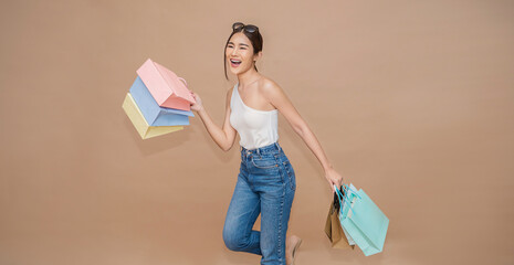 Portrait of happy beautiful shopaholic asian woman carry shopping bags, summer fashion sale model Asia girl with copy space, outlet department store advertising concept isolated banner background - obrazy, fototapety, plakaty
