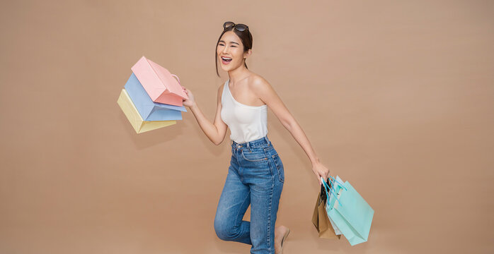 Portrait of happy beautiful shopaholic asian woman carry shopping bags, summer fashion sale model Asia girl with copy space, outlet department store advertising concept isolated banner background