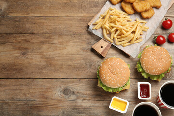 Flat lay composition with delicious fast food menu on wooden table. Space for text