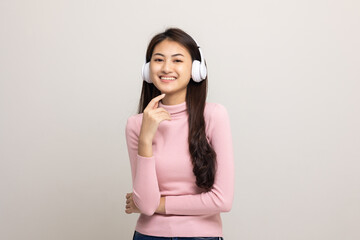 Cheerful asian female teenager listen to the music with white headphone on isolated. Beautiful young woman in pink shirt hand touch a wireless headphone having fun with the music in  room.