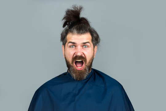 Excited amazed man at the hairdresser getting a haircut. Hipster client in hairdressing salon. Professional barber styling hair of his client.