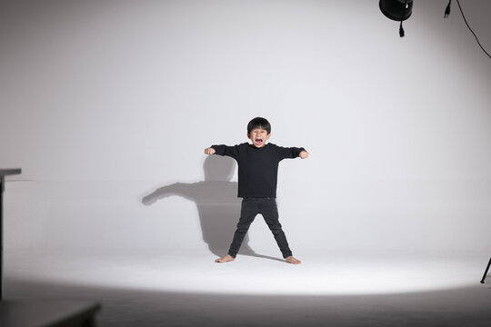 Asian boy about 5 years old practice dancing on the white screen.