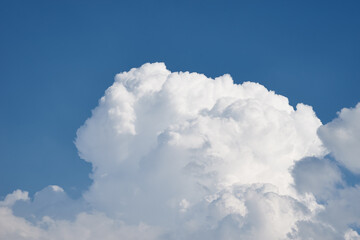 Naklejka na ściany i meble Big white fluffy clouds on clear blue sky. Cloudy sky background with copy space. Cumulus cloud close up
