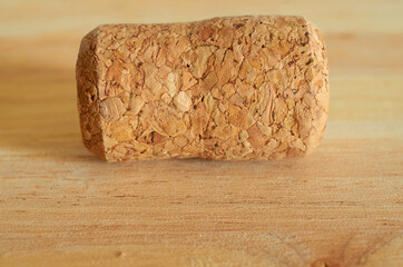 One champagne cork is lying on a wooden table. Close up