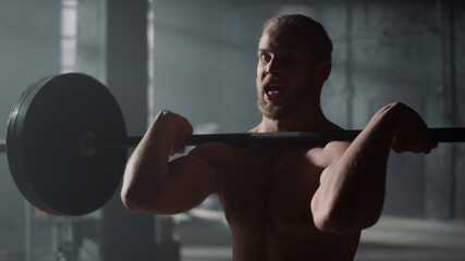 Man lifting weights in gym. Strong guy shoulder press exercise during training