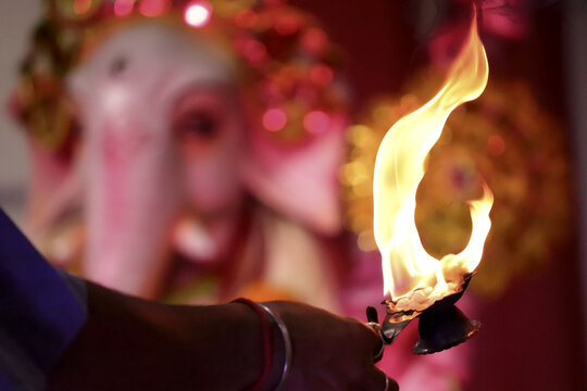 Close-up of a priest offering sacred flame to an idol of the god Ganesha