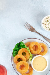 Squid rings. Delicious calamari with a dip and a green salad leaf, shot from the top with copy space