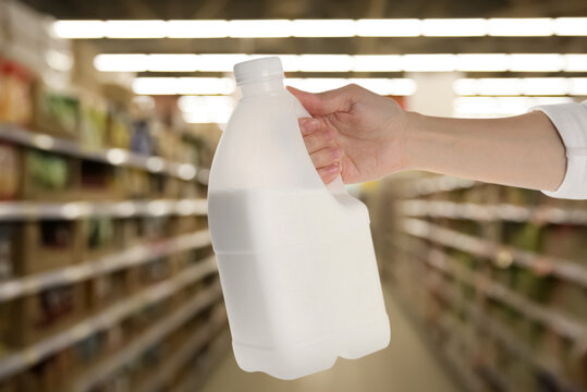 Woman Holding Gallon Bottle Of Milk In Supermarket, Closeup