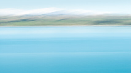 Abstract image of turquoise colours of Lake Pukaki with snow-capped mountains in the distance. Image taken by intentional camera movement. South Island.