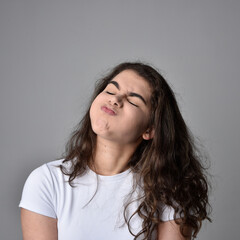 Close up portrait of young woman with natural brown hair, over the top facial expressions on light grey studio background.