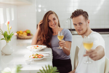 Obraz na płótnie Canvas Happy couple love drinking champagne together while cooking in the kitchen. Young loving man and woman drinking champagne together in kitchen room.