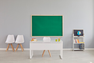 Modern school classroom interior with teacher's desk and chalkboard, space for design. Empty...