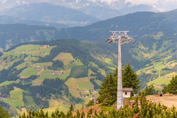 Obraz premium Construction of a new ski lift. Support pole, no steel ropes, standing alone on the slope. Upper ski lift station. Yellow crane at the construction site, a vast panorama of the mountains