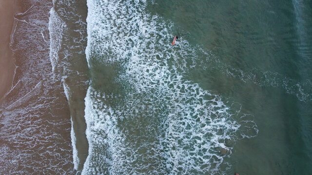 Lone surfer riding out into the sea waiting to catch waves crashing against the beach, summer vibes, coastal Victoria, Great Ocean Road, Australia