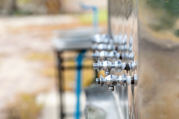 Close up of drinking faucets attached to the drinking water dispenser, Stainless steel drinking water faucets. Selective focus on first cooler faucets with copy space. Healthy drinking concept.