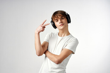 guy in white t-shirt with headphones music technology light background