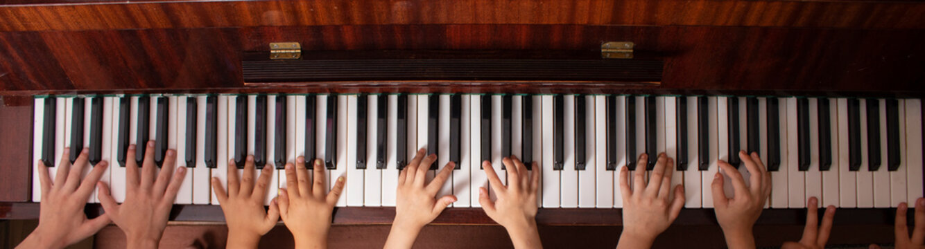 Young friends play the piano. Kids Hands touching piano keyboard