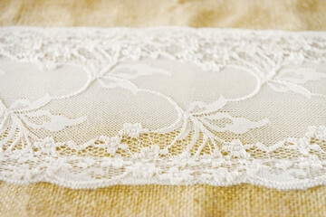 Gros-plan d'une dentelle d'un chemin de table blanc sur un tissu en lin beige