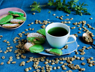 tasse grüner kaffee mit kaffebohnen und mit grünen zuckerguss überzogenen keksen