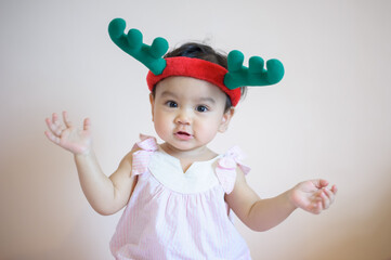 Portrait of happy cute little Asian girl who has just had milk teeth laughing. She wears antler hat and look at camera, isolated on the background. baby expression concept