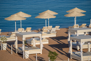 Luxury sand beach with beach chairs and white straw umbrellas in tropical resort in Red Sea coast in Egypt, Africa