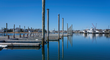 Boas and docks at the marina on blue tranquil sea water and clear blue sky.
