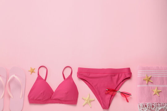 Stylish bikini and beach accessories on pink background, flat lay. Space for text