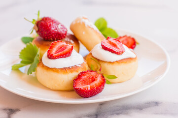 Sweet cheese pancakes on plate served strawberries and mint. Cottage cheese pancakes, syrniki, ricotta fritters, curd fritters.