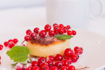 Syrniki cottage cheese fritters with summer berries on white plate, wooden table background. Russian sweet breakfast cheese pancakes