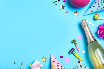 Flat lay composition with birthday decor and bottle of sparkling wine on light blue background,...