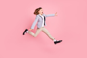 Fototapeta na wymiar Full length profile photo of astonished small girl jump look empty space wear blazer trousers shoes isolated on pastel pink color background