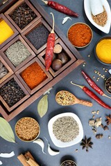 Variety of Indian spices and herbs in a wooden box. Multicolored spices in a wooden organizer, top view. Seasoning background. Bay Leaf, Black Pepper, Cinnamon, Cloves, Coriander, Turmeric, red chili.