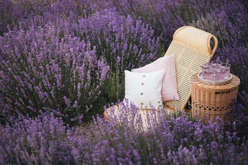 Wicker chair and table with fresh homemade lemonade in lavender field.